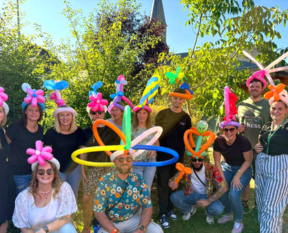 Erwachsene mit bunten Ballonhüten genießen Ballonkunst auf einer Feier – Ballonkünstler für Hochzeiten, Firmenfeiern und Events im Rhein-Main-Gebiet.