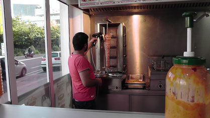 Imbiss-Inhaber macht mir einen Döner mit Pommes Frites