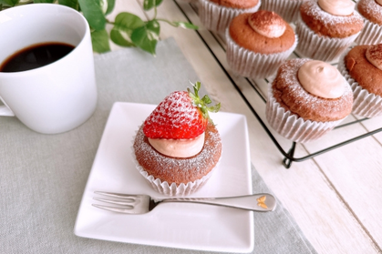 いちごとクリームがのったマフィンのお皿。コーヒーのマグカップ。ケーキクーラーに焼きたてのマフィンが並んでいる。