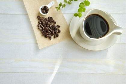 コーヒーの入ったカップ＆ソーサ。ユーカリの小枝。計量スプーンとコーヒー豆。