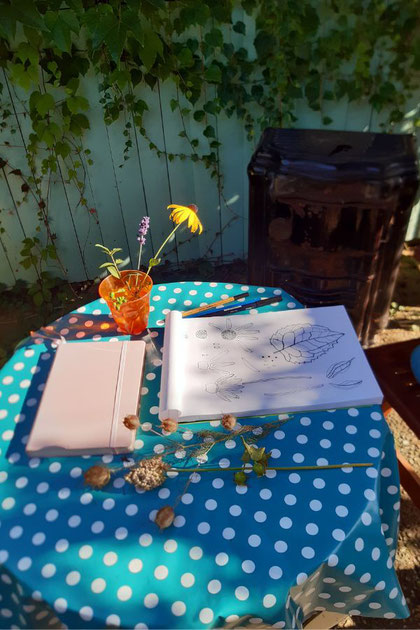 Tisch mit Zeichenblock, Blumenvase und Trockenblumen
