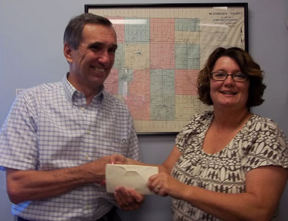 Eva Fisher (right), president of the McDonough County Genealogical Society, presents a donation to Dan Wise, president of the McDonough County Historical Society, supporting the cemetery sign project.