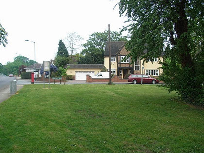 Whateley Green. Water Orton Road runs to the left of the picture; the Chester Road is out of sight on the right. The single-story white house behind the pillar box was the lodge of Whateley Hall.