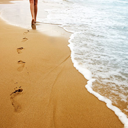 Füße am Meer im Sand und Wellen