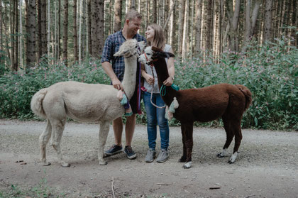Zwei Alpakas begleiten zwei Menschen, die sich Zeit füreinander nehmen