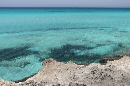 Kleines Stück schroffer hellgrauer Felsen an der Punta della Suina mit durchsichtigem türkisfarbenem Meerwasser