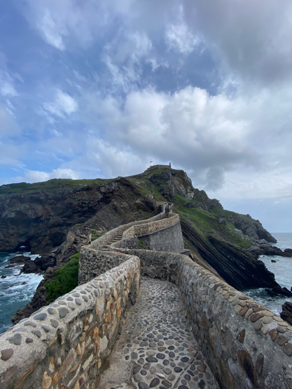 l'eremo di San Juan Gaztelugatxe visto dal basso, con una scalinata in pietra per salire la collina dell'isolotto