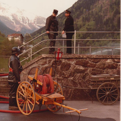 Löschdienst auf dem Schulplatz, im Hindergrund: Elektrikerwagen