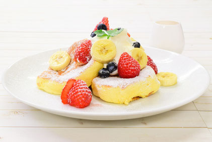 いちご、バナナ、ブルーベリー、生クリームが盛り付けられたパンケーキのお皿。