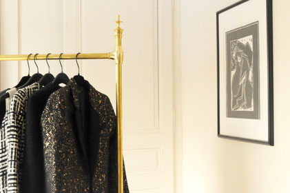 portant pour vêtements en laiton doré de style ancien en situation avec des vêtements suspendus à des cintres dans un décor chic, sobre et élégant