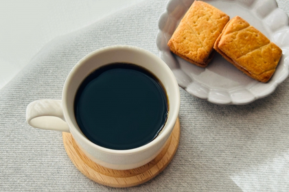 コーヒーの入ったマグカップ。バターサンドビスケットの小皿。