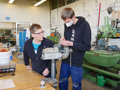 Arbeitserzieherin mit einem Jugendlichen in Metallwerkstatt