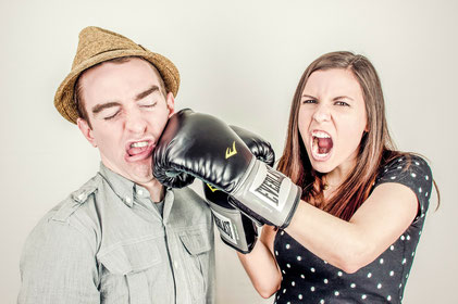 Mann bekommt Schlag ins Gesicht von Frau mit Boxhandschuh. Steht für Streit in der Beziehung