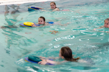 Kinder üben mit Schwimmbrett im Wasser ihre Technik im Schwimmkurs Delfine des BSV Achim.