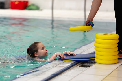 Kind erhält am Beckenrand Anleitung und Trainingsmaterial im Schwimmkurs Delfine des BSV Achim.