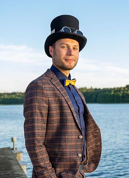 Magier Johannes verzaubert lachende Zuschauer an einem runden Tisch mit kleinen roten Bällen