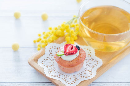 生クリームといちごがのった焼き菓子と紅茶のカップ。ミモザの花。