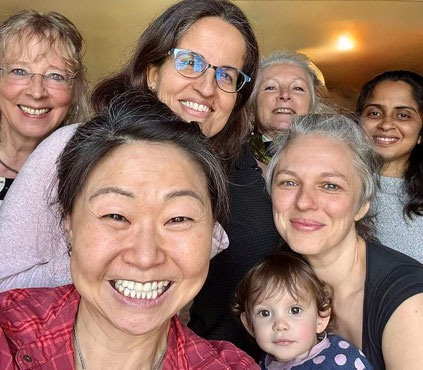 Ein Gruppenfoto mit mehreren Frauen verschiedenen Alters und einem Kind, die glücklich lächeln und sich gut verstehen. 