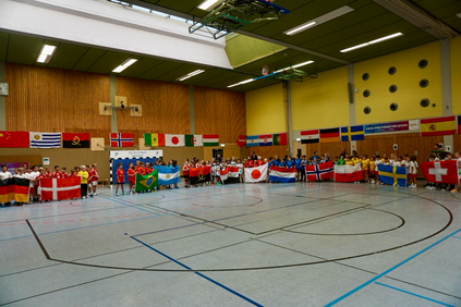 Viele Kinder halten in einer Sporthalle die Flaggen unterschiedlicher Länder