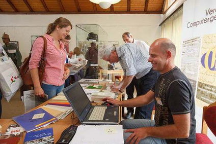 Familienforscher mit Informationsmaterialien und Personen am Stand