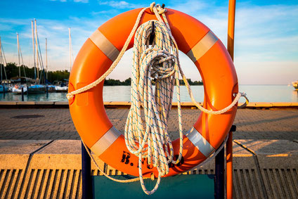 Oranger Rettungsring auf einer Seebrücke als Zeichen von Reiseschutz