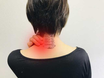 首を押さえる女性の後ろ姿