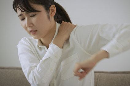 辛そうに肩を動かす女性