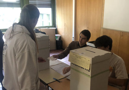 Ausgabe der Stimmzettel durch die Wahlhelfer nach penibler Überprüfung von Wählerverzeichnis, Wahlbenachrichtigung und Ausweis.