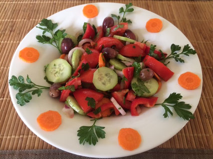 Salat aus Gurken, Karotten, Zwiebeln und Tomaten schön dekoriert in einem weißen Teller