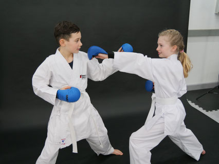 Zwei Kinder im Karate Anzug zeigen Karate Techniken