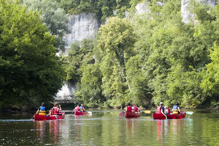 Canoës naviguant sur la rivière Dordogne au pied des falaises et des châteaux.