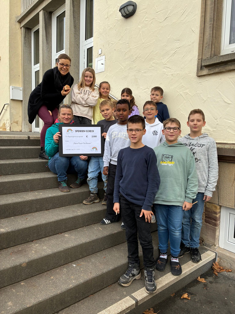 Die Kinder der Kinderkonferenz übergeben gemeinsam mit der Schulleiterin Frau Mühlhausen die Spende von 2000 Euro an die "Kleinen Riesen".