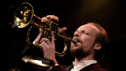 Trompeter Johannes Stange im Anzug spielt Flügelhorn