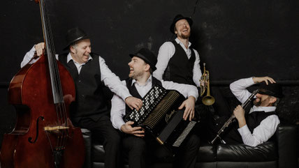 Das Klezmerquartett Heidelberg, lachend und Späße machend auf einem Sofa