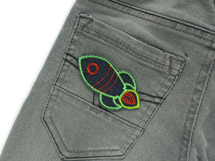 eine kleine Rakete zum aufbügeln in Neongrün auf der Gesäßtasche einer Jeanshose
