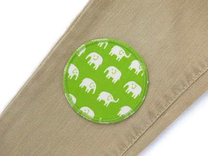 ein hellgrüner Hosenflicken mit kleinen weißen Elefanten wurde als Stoffflicken auf eine Kinderhose gebügelt.