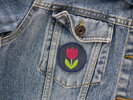 ein Patch zum aufbügeln mit gestickter Tulpe in pink als Accessoire auf einer Jeansjacke
