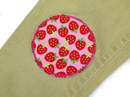 !B auf eine Kinderhose mit Löchern wurde als Flicken ein Patch mit Erdbeeren aufgebügelt.