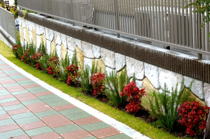 自然石の壁＋彩りの植栽 → 美しいグリーンベルト。手前の歩道もカラー。