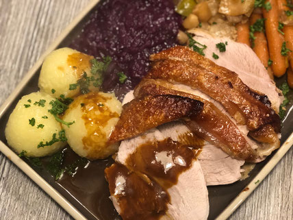 Schweinebraten auf grauer Servierplatte angerichtet