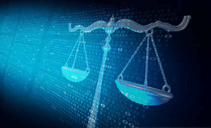 Scales of justice in front of dark computer screen showing lines of binary code fade out into the back