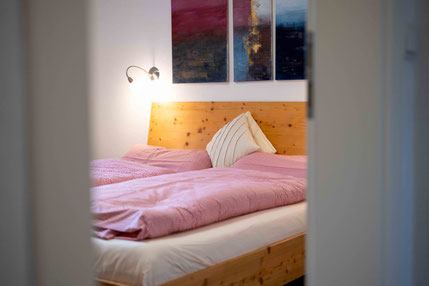 Doppelbett mit rotkarierter Bettwäsche und Nachttischlampen