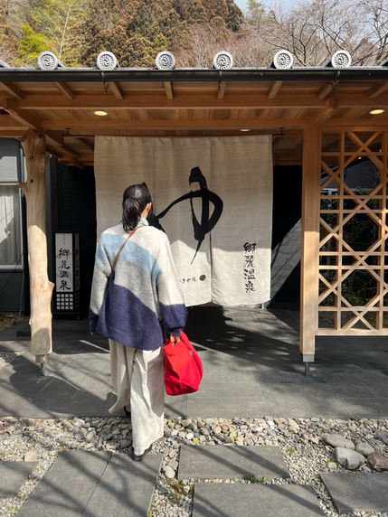 高知の貸切風呂「郷麓温泉」の暖簾をくぐる赤いバッグを持つ女性