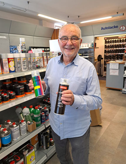 Inhaber Hans-Herman Lipp hält in jeder Hand eine Spraydose mit abgefülltem Autolack 