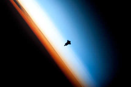 Space Shuttle Endeavour silhouetted against the atmosphere. The orange layer is the troposphere. The shuttle is actually orbiting at an altitude of more than 320 km. By NASA/Crew of Expedition 22, via Wikimedia Commons