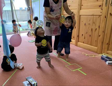 今週はずっと雨で、なかなか外で遊ぶことができずにいましたが、室内で体をたくさん動かして遊びました。そらぐみさんと、ひかりぐみさんは電車に紐をつけてもらって引っ張って遊びました。他にもすずらんテープ遊びをしました。手を伸ばして触り、揺れているボールを見て嬉しそうにしていました。
