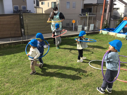 電車ごっこをしている子もいて、「いっしょにはいろう！」とお友達を誘って二人でフラフープに入ったり、フラフープをつなげたりして、「でんしゃです！しゅっぱつします！」「しんかんせんだよ！」と、楽しそうに園庭を走っていました。