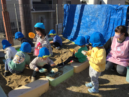 砂で大きな山を作ったり、「でんしゃ、はしる？」「トラックにいっぱいおすないれるね！」「はこぶよー！」とみんなで協力してお砂場遊びを楽しんでいました。
