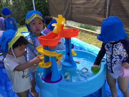 スロープに流れる水をせきとめて水をかけあっこしたり、穴の空いたカップに水を入れて「あめ！あめ！」と、手や足にかけていました。