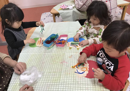 切ってある毛糸を頭に貼りました。真っ直ぐに貼る子や、色々な向きに貼る子もいました。次は何色にしようかな？と迷ったり、目がまだ貼ってないので、毛糸を目の辺りに置いて目に見立てている子もいました。どんな鬼に変身するかな？
